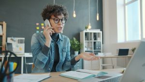 Mad woman talking on phone at desk with laptop